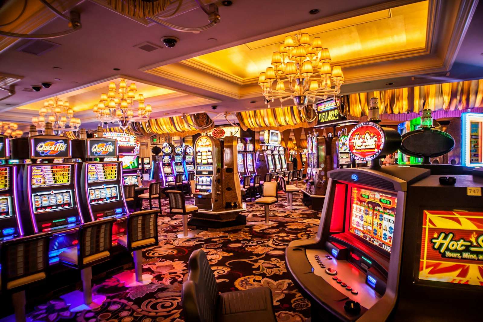 Suasana lantai kasino dengan lampu hangat dan mesin permainan